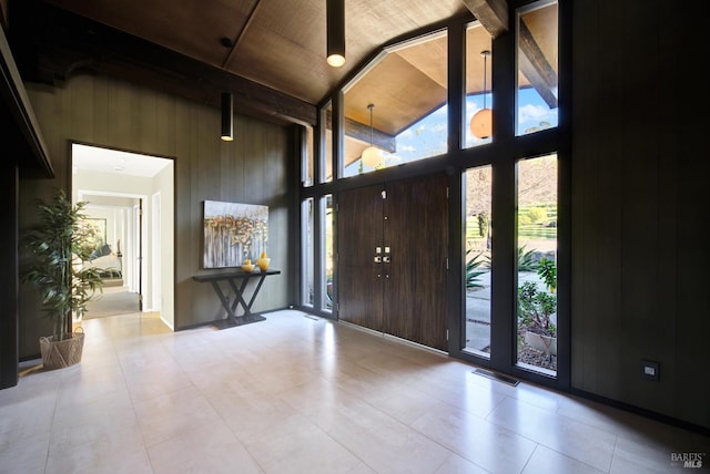 entryway with high vaulted ceiling, wood walls, and visible vents