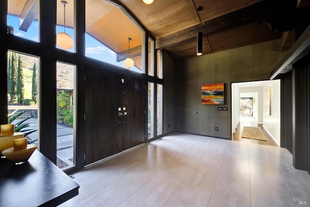 foyer entrance with a wealth of natural light, wood walls, a towering ceiling, and floor to ceiling windows