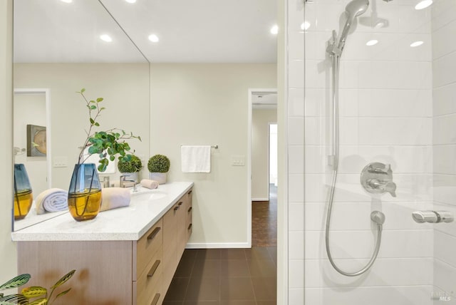 bathroom with tile patterned floors, tiled shower, vanity, baseboards, and recessed lighting