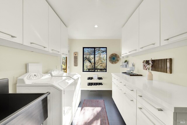 washroom featuring recessed lighting, a sink, washing machine and dryer, baseboards, and cabinet space
