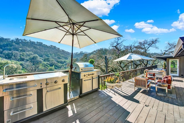 wooden terrace with an outdoor kitchen, a sink, and a grill