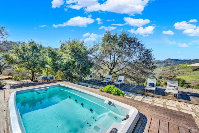 outdoor pool with hot tub deck surround and a deck with mountain view