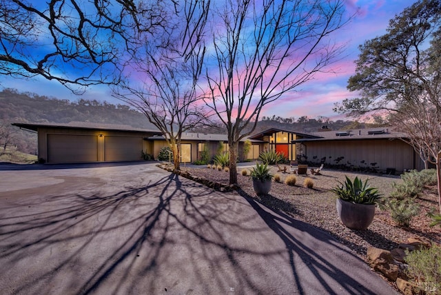 mid-century home with an attached garage and aphalt driveway