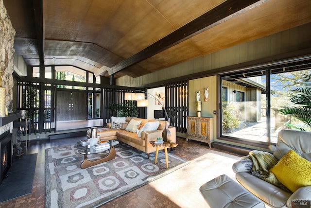 living room with a healthy amount of sunlight, vaulted ceiling with beams, and a lit fireplace
