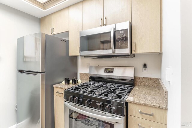 kitchen with light stone countertops, light brown cabinets, and appliances with stainless steel finishes