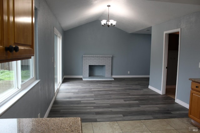 unfurnished living room featuring vaulted ceiling, dark hardwood / wood-style floors, a notable chandelier, and a fireplace