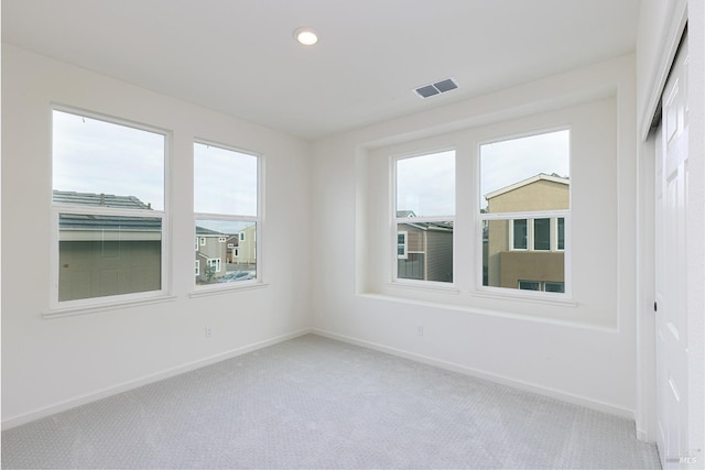 unfurnished room with light carpet, a wealth of natural light, visible vents, and baseboards