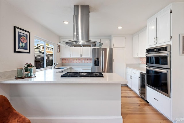 kitchen with wine cooler, white cabinetry, appliances with stainless steel finishes, kitchen peninsula, and island exhaust hood