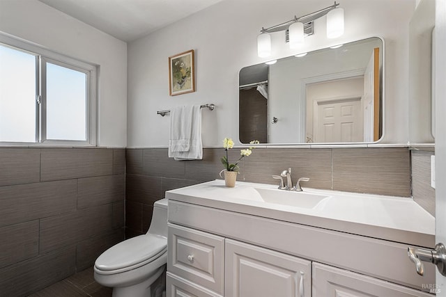 bathroom with vanity, tile walls, and toilet