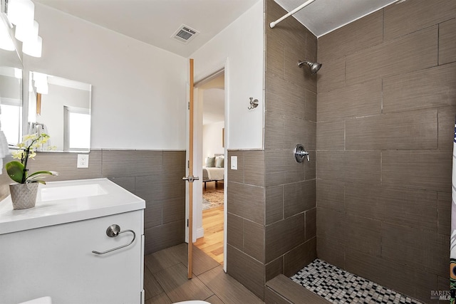 bathroom with vanity, tiled shower, and tile walls