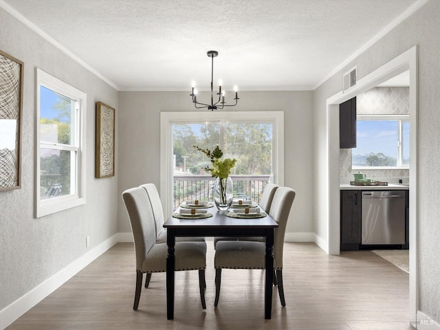 dining room with a textured ceiling, a textured wall, an inviting chandelier, and light wood-style floors