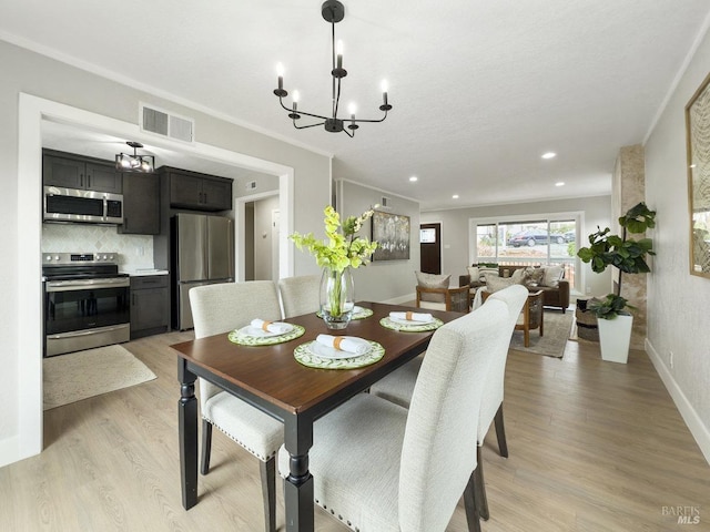 dining room featuring ornamental molding, baseboards, a chandelier, visible vents, and light wood-style flooring