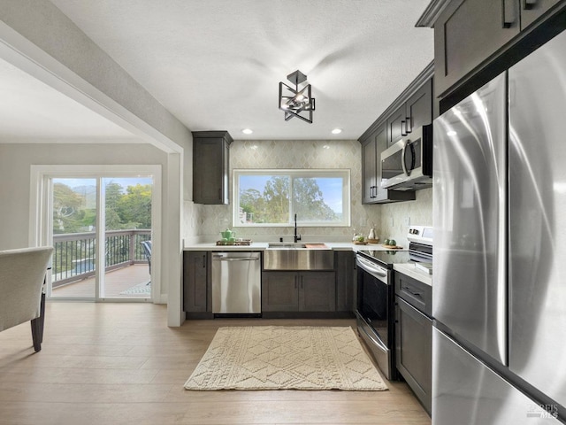 kitchen featuring stainless steel appliances, sink, decorative backsplash, and light hardwood / wood-style flooring