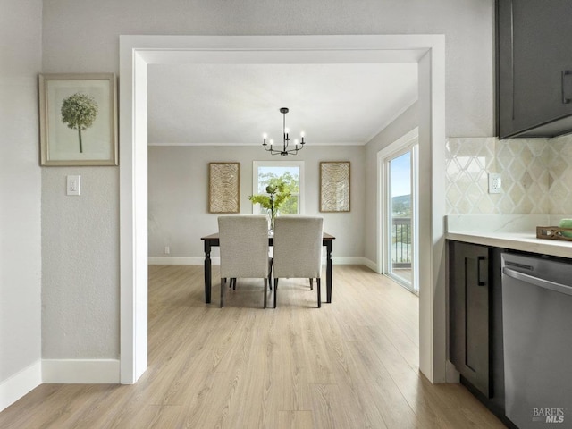 dining space with an inviting chandelier, ornamental molding, baseboards, and light wood-type flooring