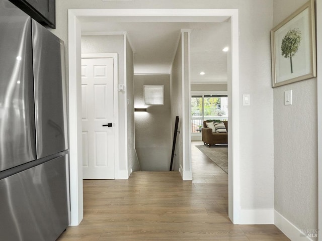hall with baseboards, an upstairs landing, ornamental molding, and light wood-style floors