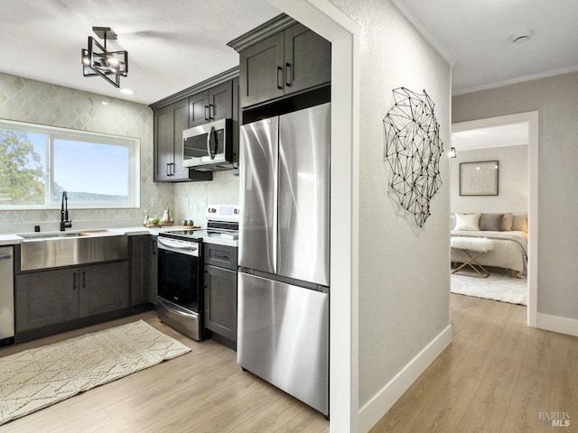 kitchen with sink, crown molding, light hardwood / wood-style flooring, appliances with stainless steel finishes, and decorative backsplash