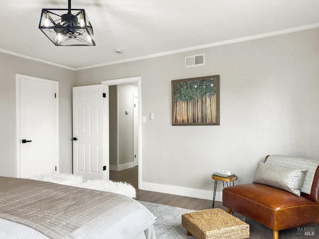 bedroom featuring crown molding, an inviting chandelier, baseboards, visible vents, and wood finished floors