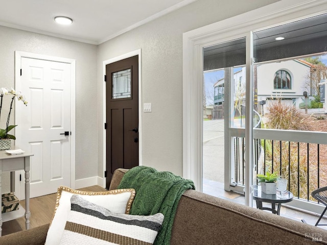 foyer with baseboards, crown molding, wood finished floors, and a textured wall