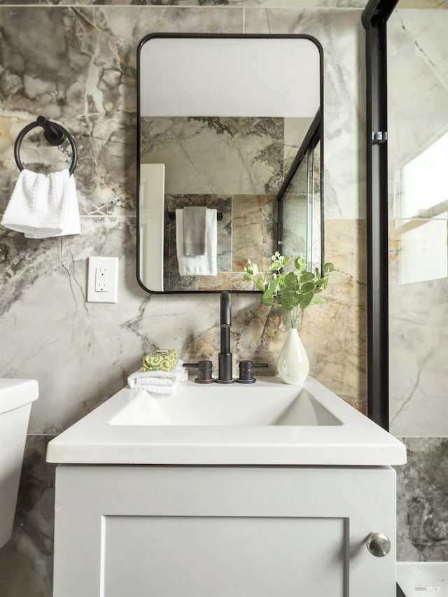 bathroom with tile walls, toilet, and vanity