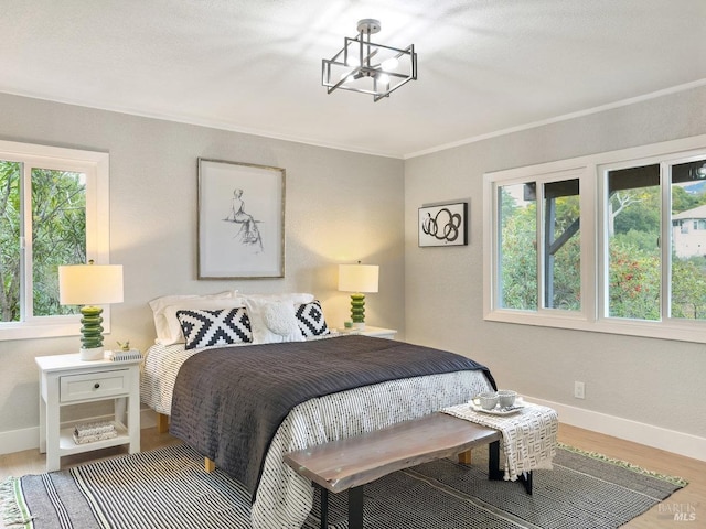 bedroom featuring hardwood / wood-style flooring, crown molding, and a chandelier