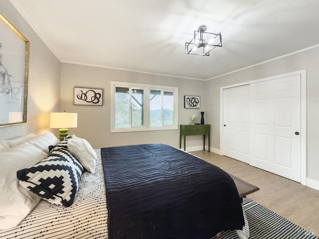 bedroom featuring a closet, crown molding, baseboards, and wood finished floors