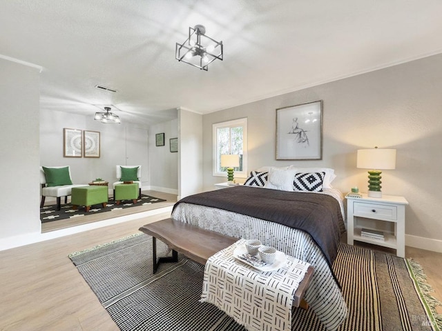 bedroom with baseboards, visible vents, a chandelier, and light wood-style floors