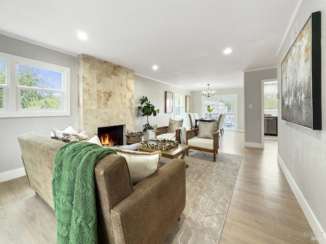 living room featuring a fireplace, crown molding, light hardwood / wood-style flooring, and a notable chandelier