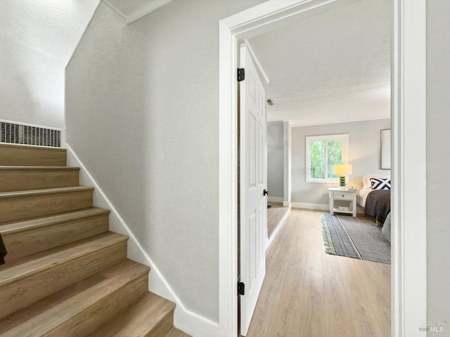 staircase with visible vents, baseboards, and wood finished floors