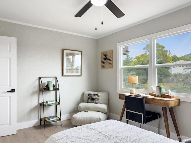 bedroom featuring multiple windows, ornamental molding, ceiling fan, and light wood-type flooring