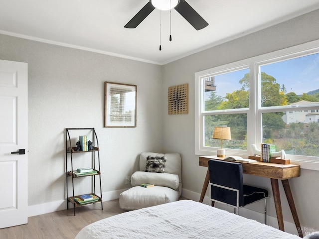 bedroom with baseboards, light wood-type flooring, crown molding, and a ceiling fan