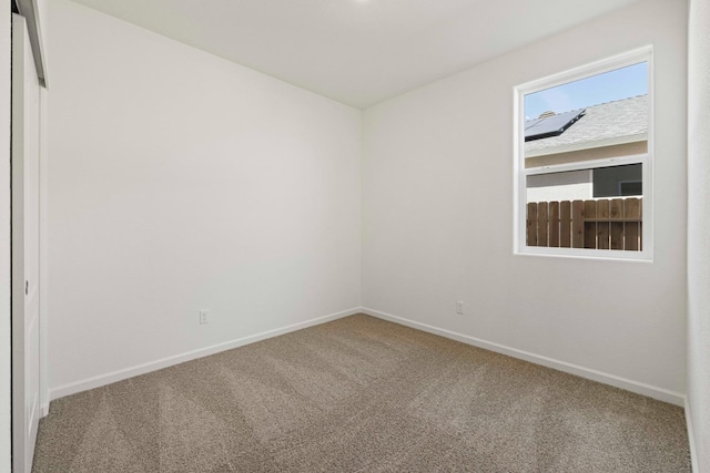 spare room featuring carpet floors and baseboards