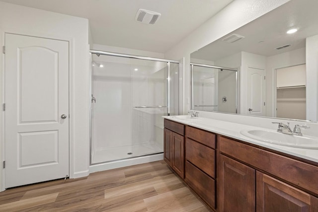 bathroom with wood-type flooring, an enclosed shower, and vanity