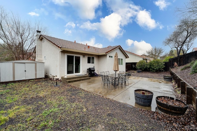 rear view of house with a storage unit and a patio