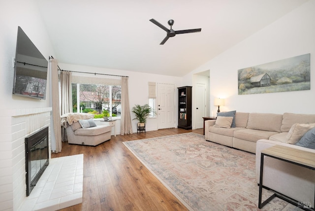 living room with ceiling fan, a fireplace, vaulted ceiling, and hardwood / wood-style floors