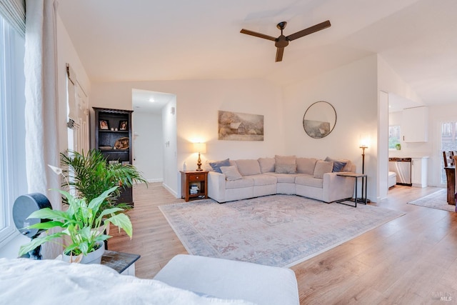 living room featuring ceiling fan, lofted ceiling, and light hardwood / wood-style floors