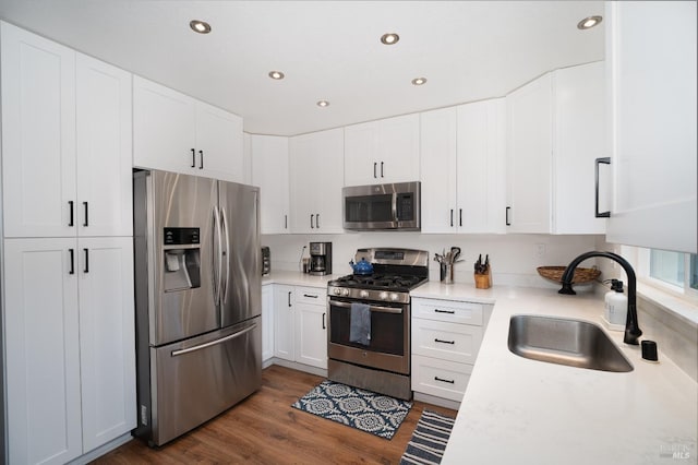 kitchen with appliances with stainless steel finishes, sink, white cabinets, and dark hardwood / wood-style floors