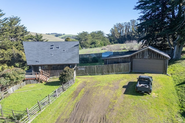 view of yard with a garage, an outbuilding, and a rural view