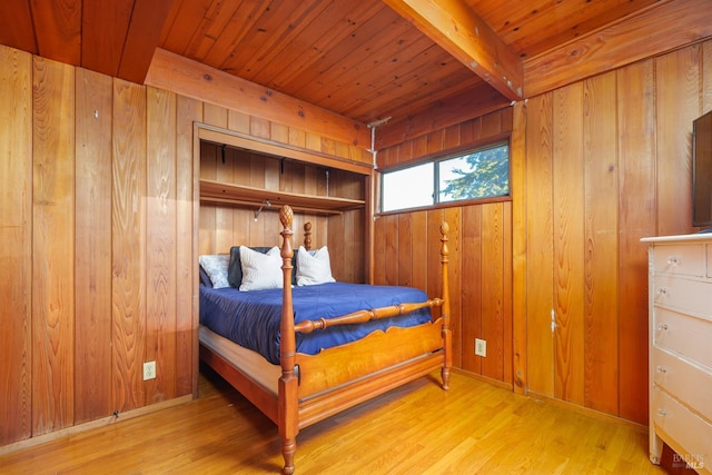 bedroom with beamed ceiling, wooden ceiling, light wood-type flooring, and wood walls