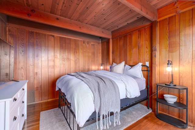 bedroom featuring beamed ceiling, wooden walls, hardwood / wood-style floors, and wooden ceiling