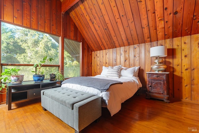 bedroom featuring vaulted ceiling, wooden walls, and light hardwood / wood-style floors