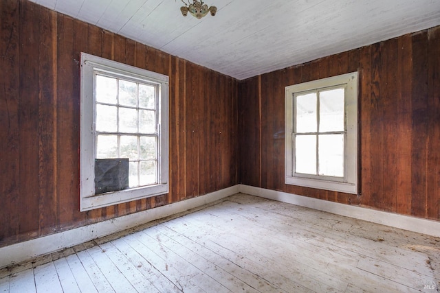 empty room featuring wooden walls and light wood-type flooring