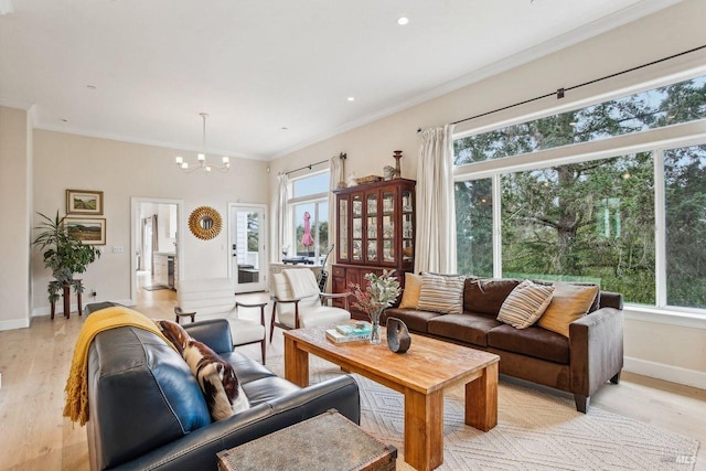 living room with an inviting chandelier, crown molding, and light wood-type flooring