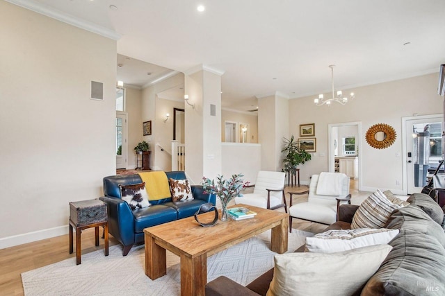 living room with ornamental molding, a notable chandelier, and light wood-type flooring