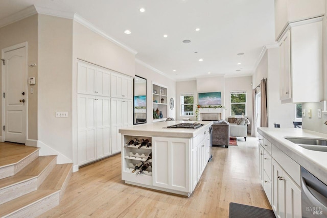 kitchen featuring sink, appliances with stainless steel finishes, a kitchen island, light hardwood / wood-style floors, and white cabinets