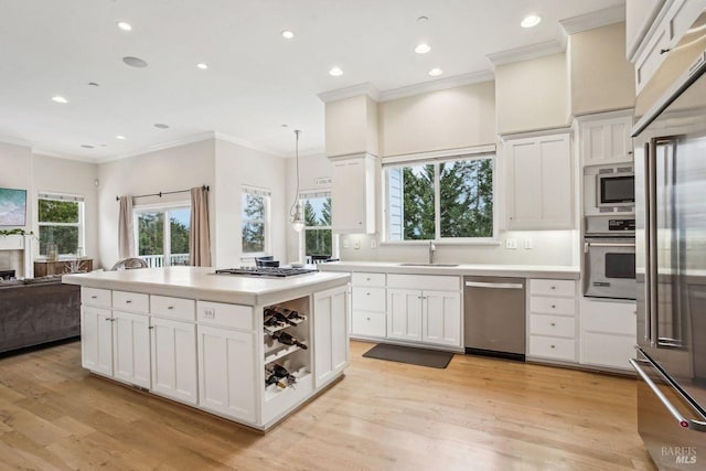 kitchen with sink, stainless steel appliances, light hardwood / wood-style floors, white cabinets, and decorative light fixtures