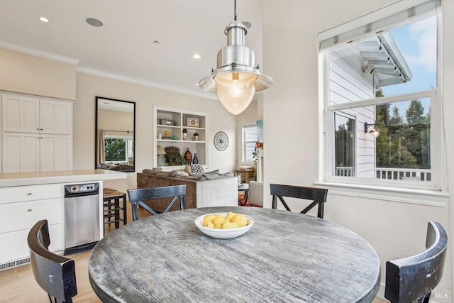 dining space with ornamental molding and light hardwood / wood-style flooring