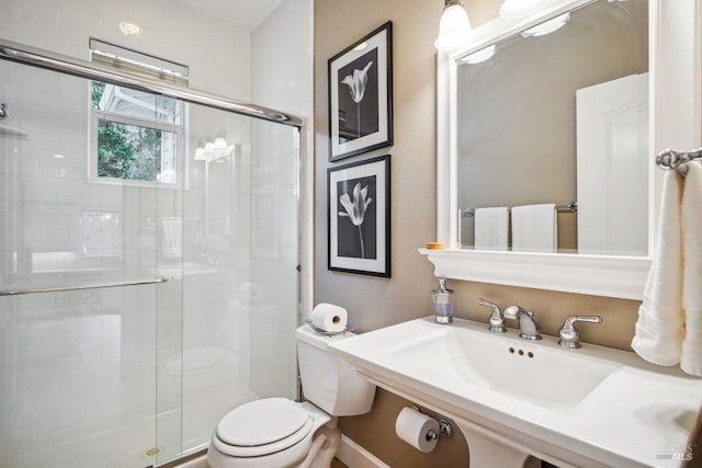 bathroom featuring sink, a shower with shower door, and toilet