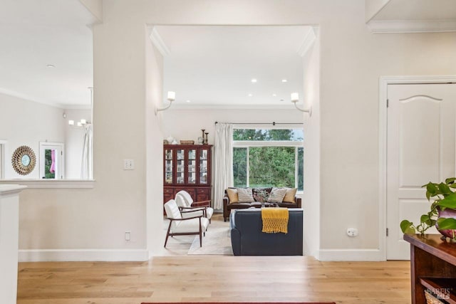 living area with ornamental molding and light hardwood / wood-style floors