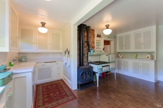 kitchen with white cabinetry, backsplash, and a wood stove