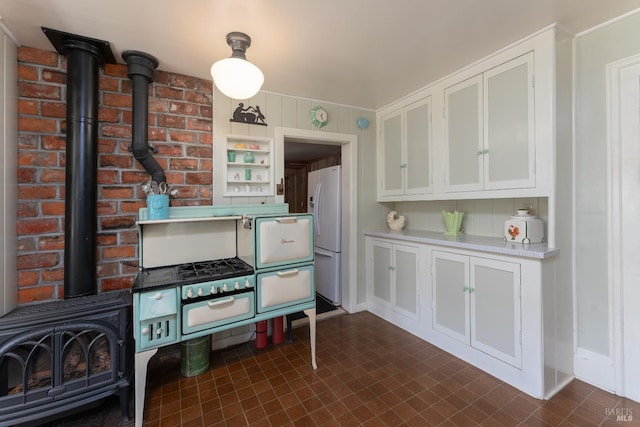 kitchen featuring white refrigerator, white cabinets, and a wood stove